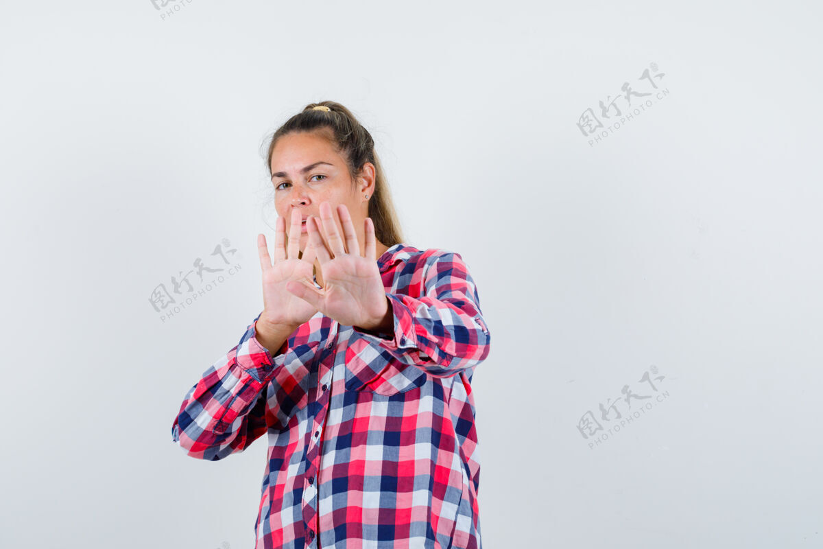 视图照片中的年轻女士穿着格子衬衫做着停车的手势 看上去很害怕年轻女性害怕