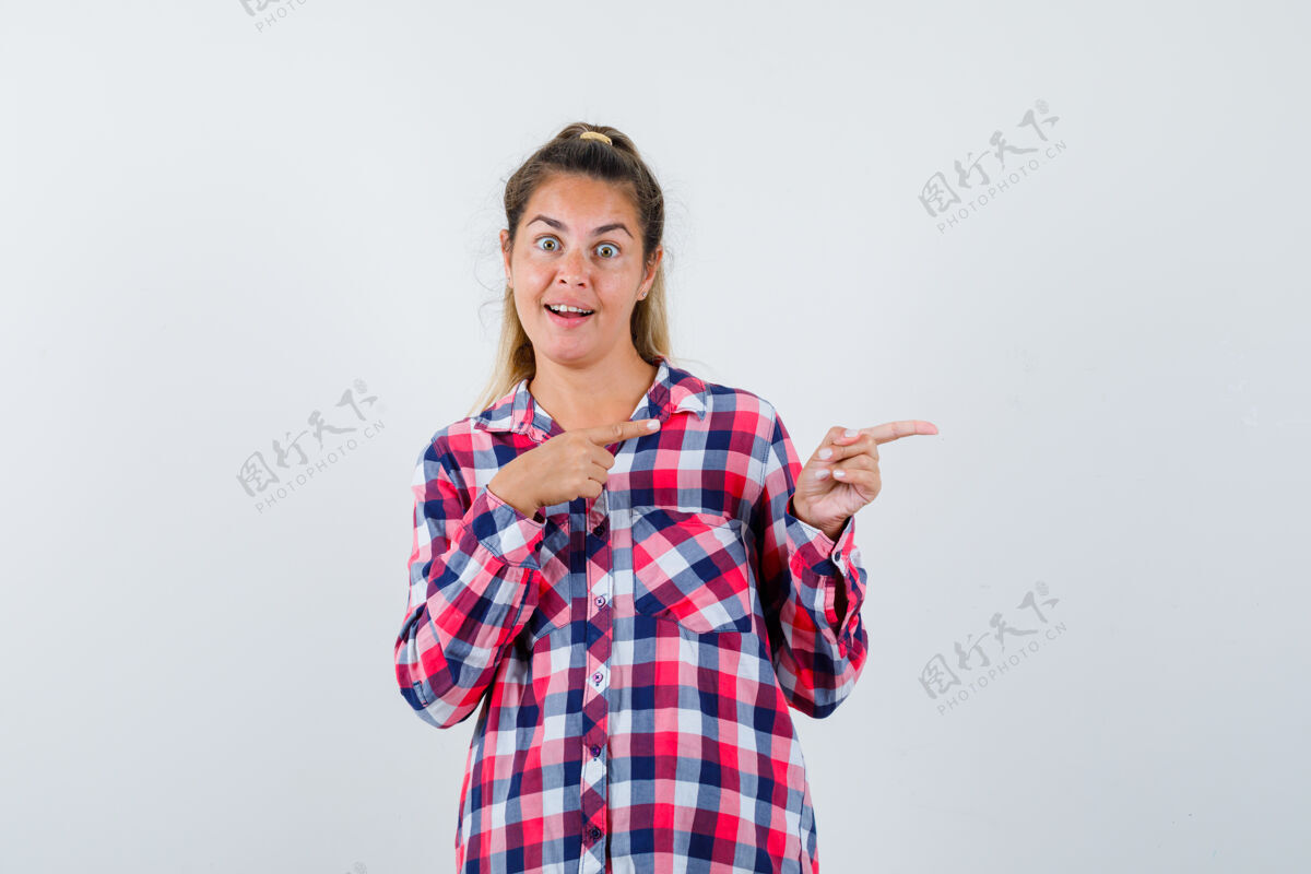 自然照片中的年轻女士穿着格子衬衫指着右边 看上去很开心侧线视图格子
