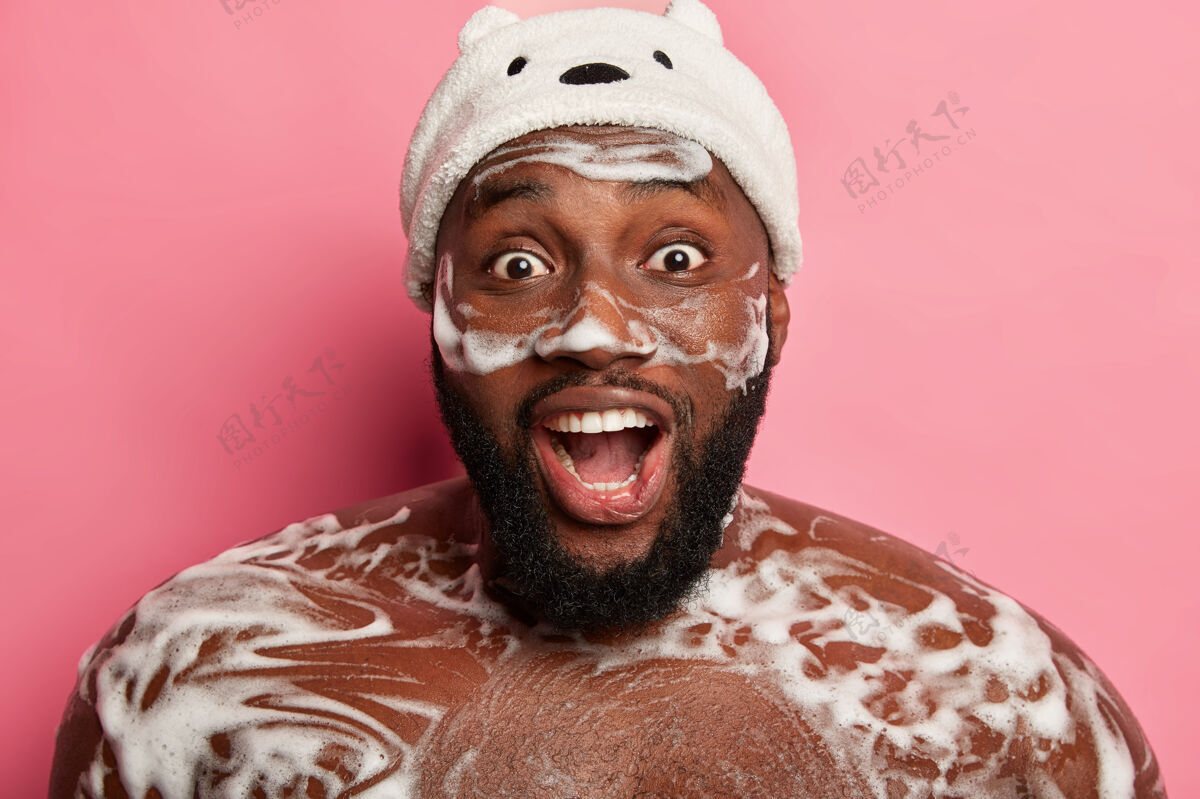 男人令人惊讶的情绪深色皮肤的男人有清爽的淋浴 泡沫在身体上 使用化妆品的男人 享受日常例行冲洗 张嘴从兴奋快乐微笑洗脸