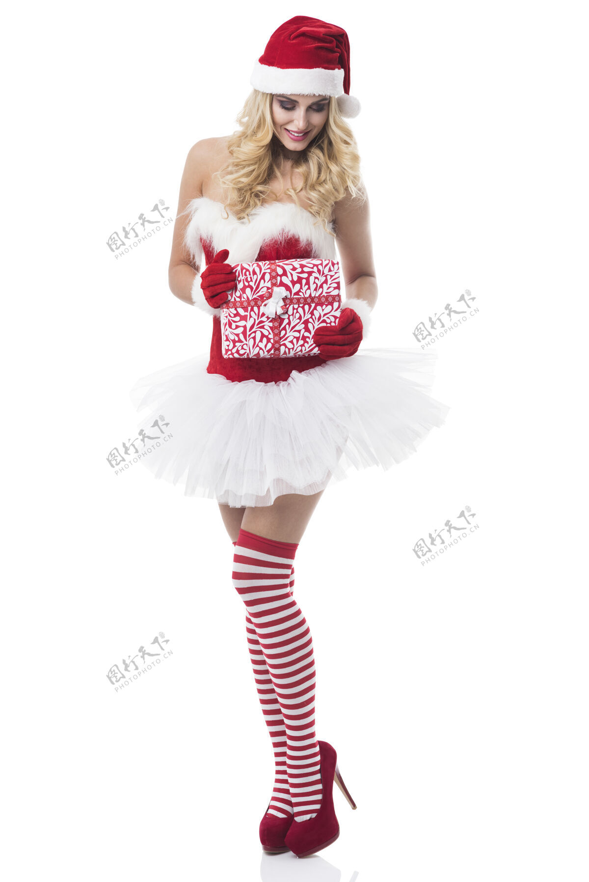 袜子穿着圣诞老人服装的性感女人在白墙上摆姿势卷发圣诞老人皮草