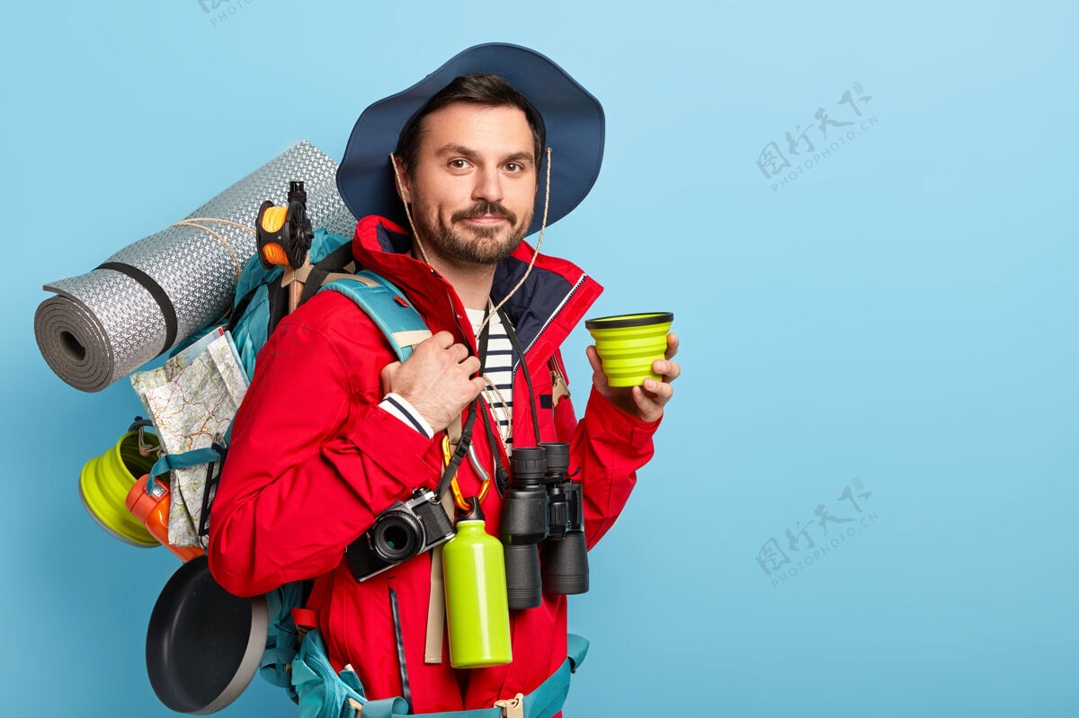 旅行者严肃的男性游客携带背包和必要的设备为旅客 喜欢长途旅行 喜欢积极的假期 喝咖啡姿势衣服人