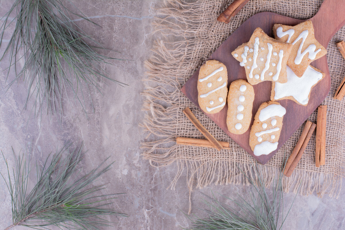 圣诞节圣诞姜饼呈椭圆形和星形 放在木板上 周围放着肉桂棒粗麻布饼干奶油