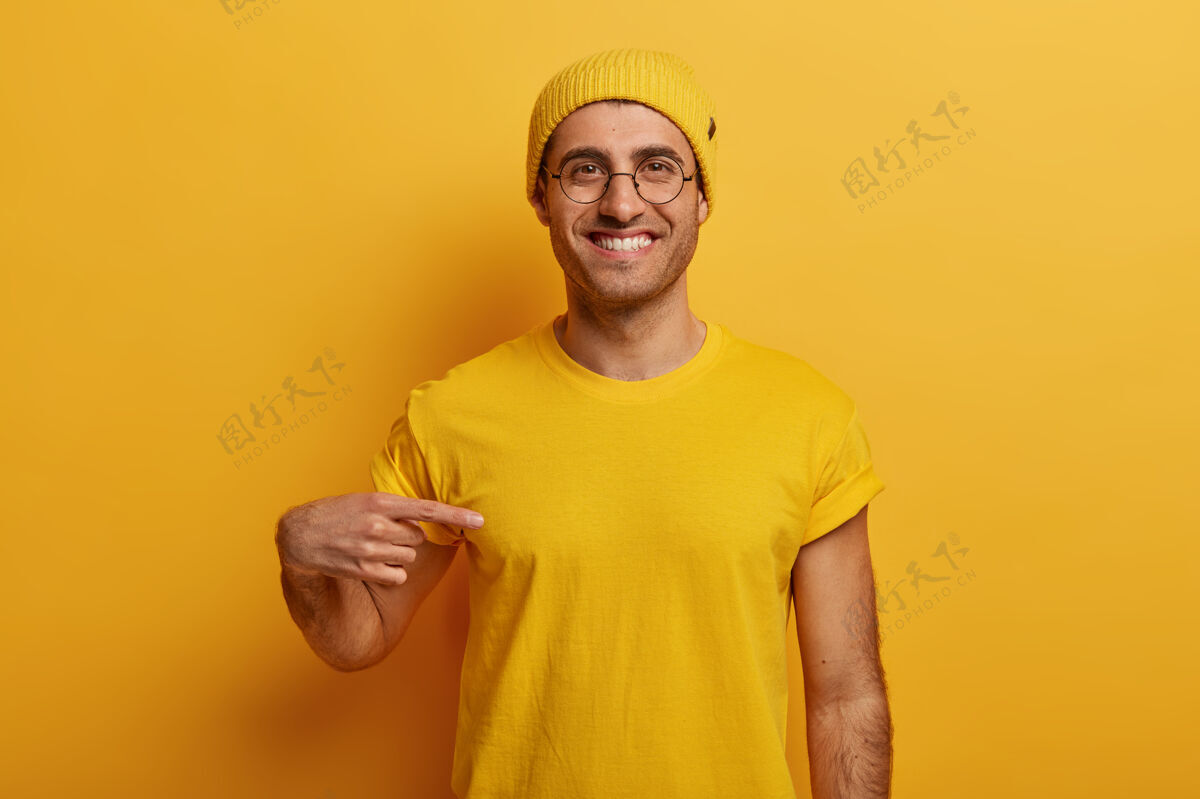 男性开朗男子半身镜头指向黄色t恤 表情欢快 宣传新装 在明亮的背景下摆姿势人广告穿