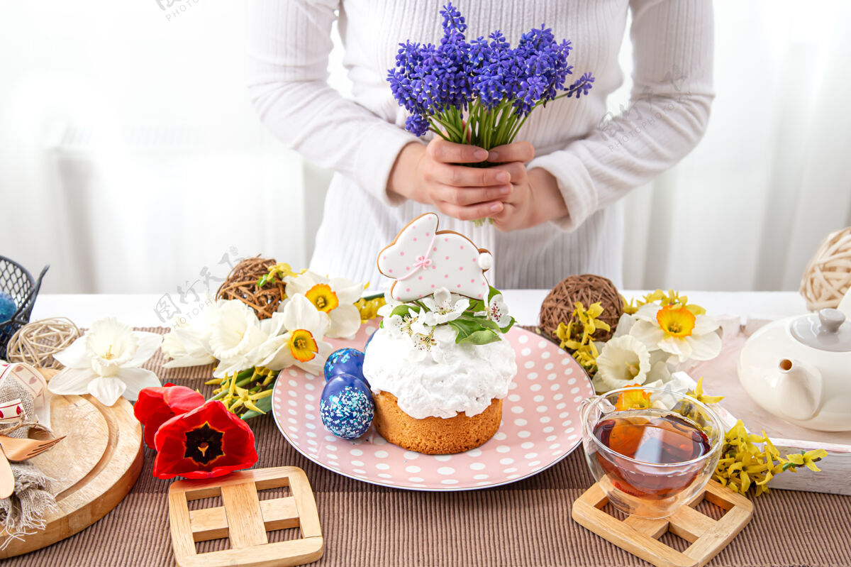 设置一个女人用鲜花装饰一张桌子复活节的概念节日蛋糕茶