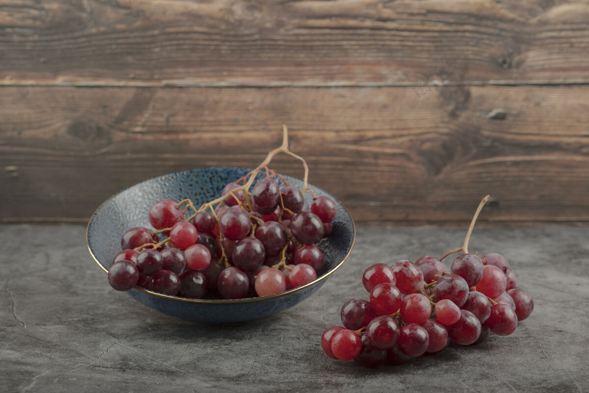 食品大理石桌上放着一盘深红色成熟的葡萄健康浆果甜味
