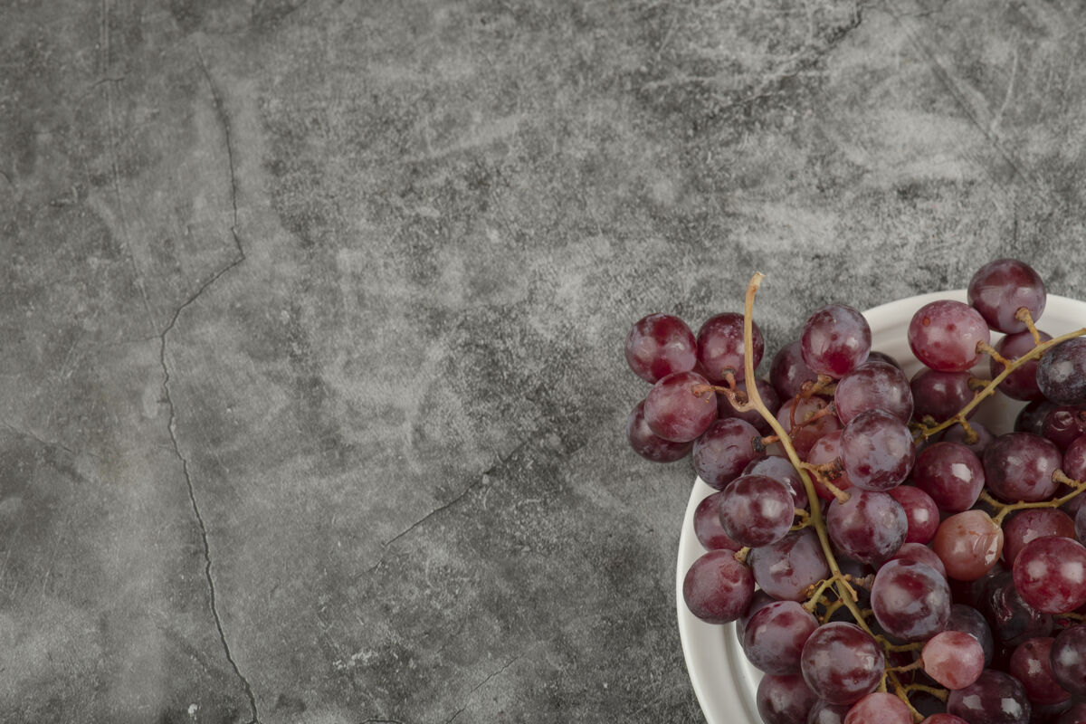 红色大理石桌上摆着一盘白色的红葡萄营养健康新鲜