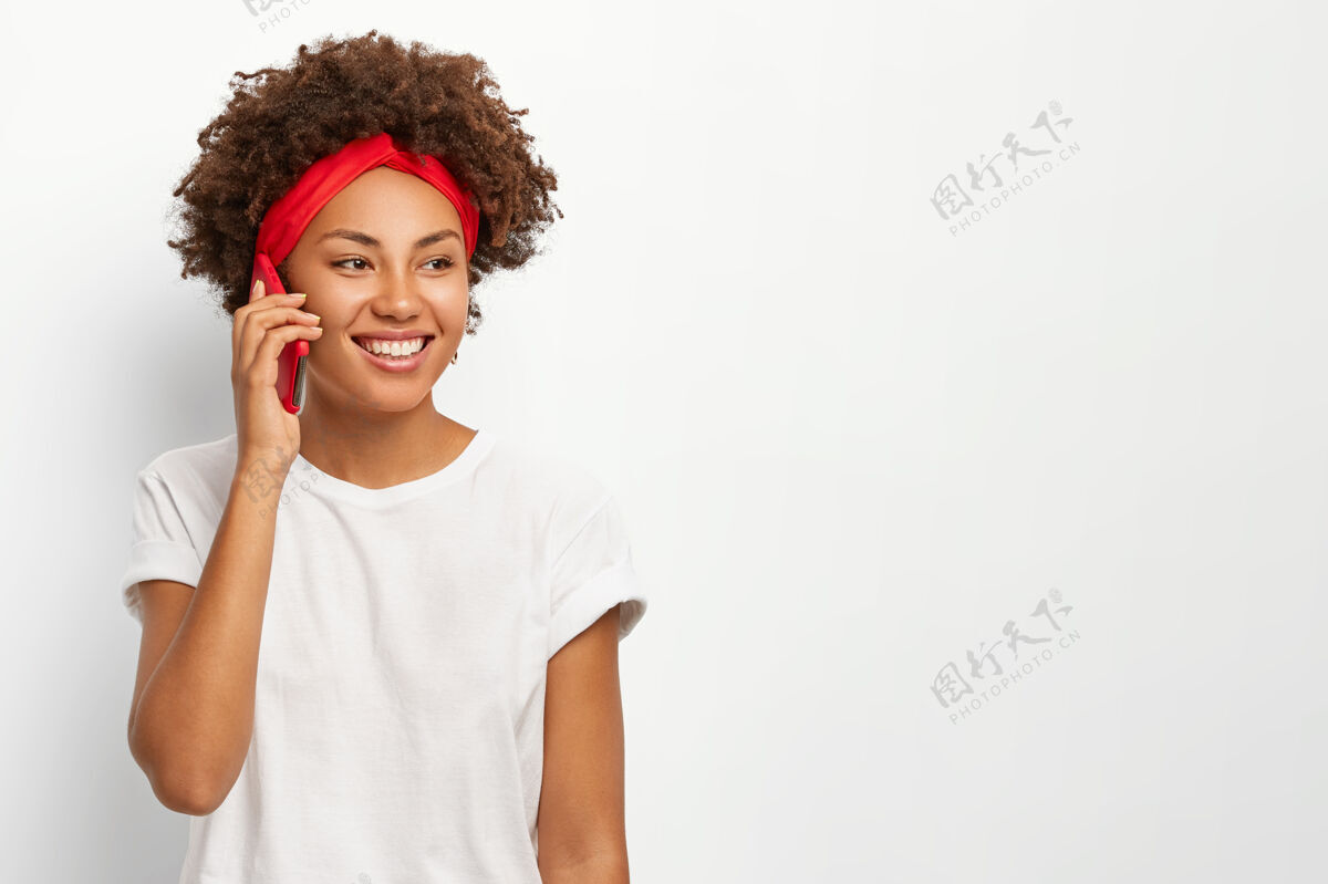 享受快乐的卷发非洲女人把手机放在耳边 享受愉快的交谈 积极的微笑女性打电话快乐