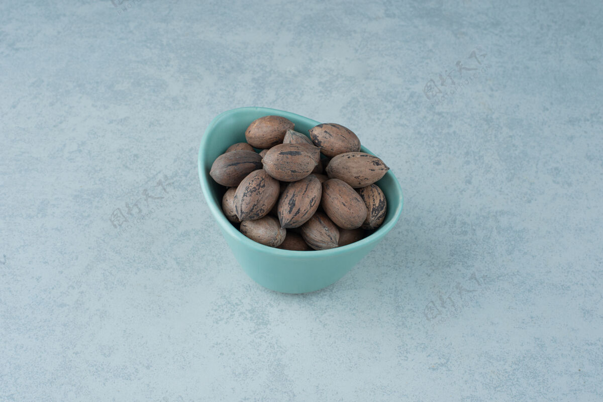 吃在大理石背景上放满坚果的蓝色小盘高质量照片盘子健康坚果