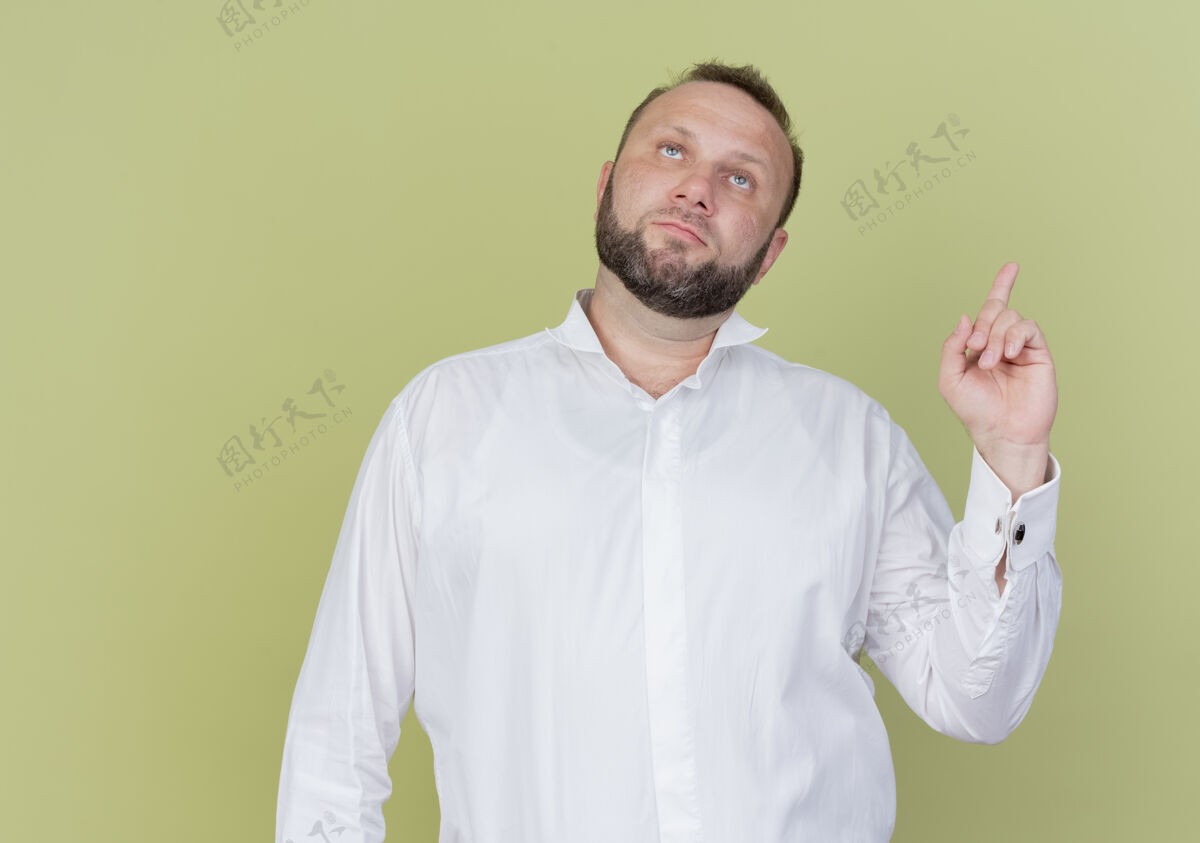 手指一个留着胡子的男人 穿着白衬衫 抬起头 露出食指 严肃的脸 站在光墙上穿光严重