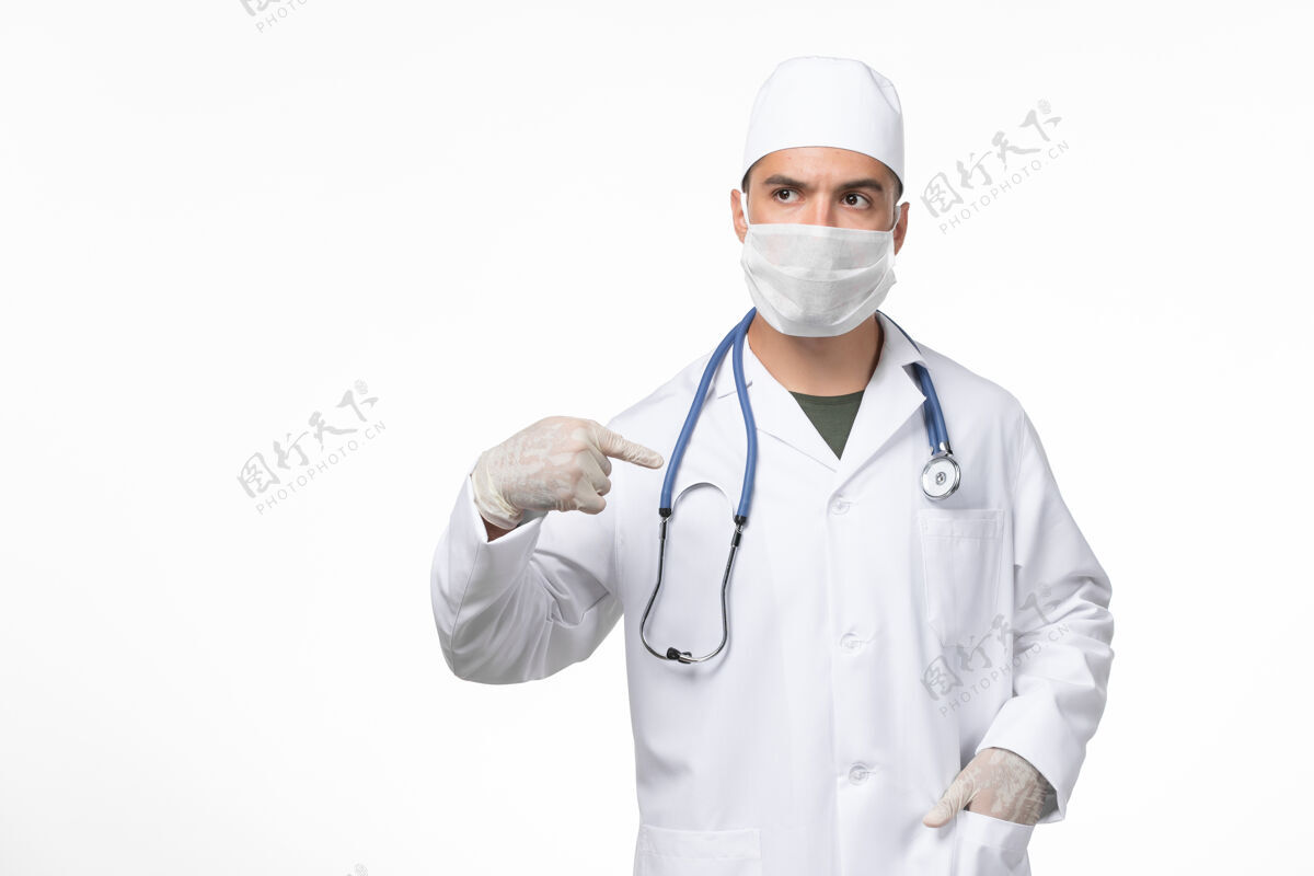 医疗正面图：男医生穿着医疗服 戴着口罩 对抗白色墙壁上的冠状病毒药物大流行视图男人穿