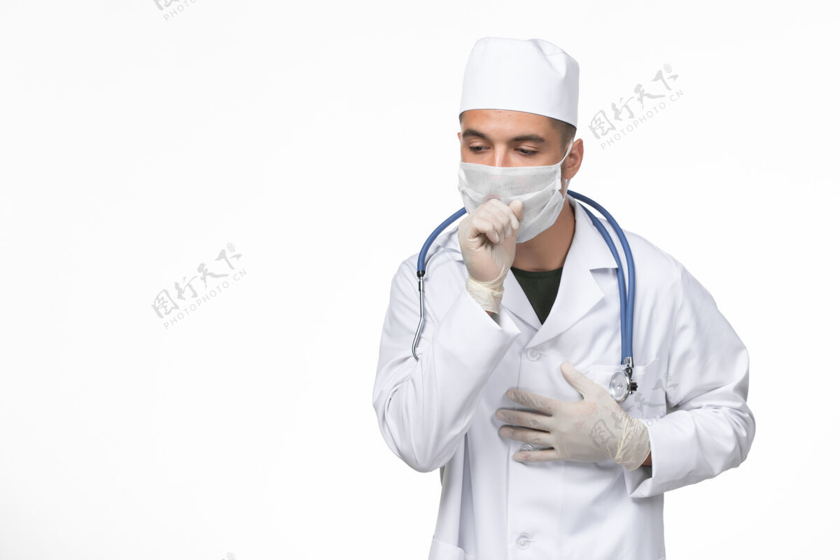 西装正面图：男医生穿着医疗服 戴着口罩 对抗白色墙壁上的冠状病毒性咳嗽病毒性疾病隔离大流行视图医疗实验室外套