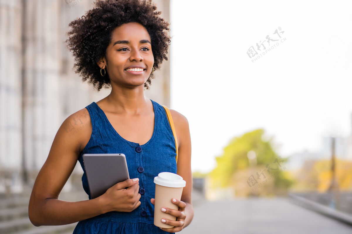 休闲一张非洲女商人的肖像 她手持一台数码平板电脑和一杯咖啡 站在户外的街道上商业和城市概念人科技步行
