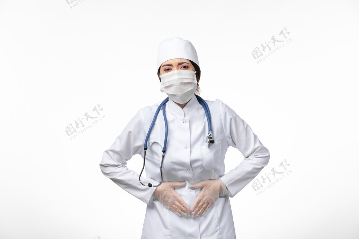 疾病正面图：女医生身穿白色无菌医疗服 戴口罩 因冠状病毒-胃痛白壁病病毒冠状病毒-大流行性疾病视图医生正面