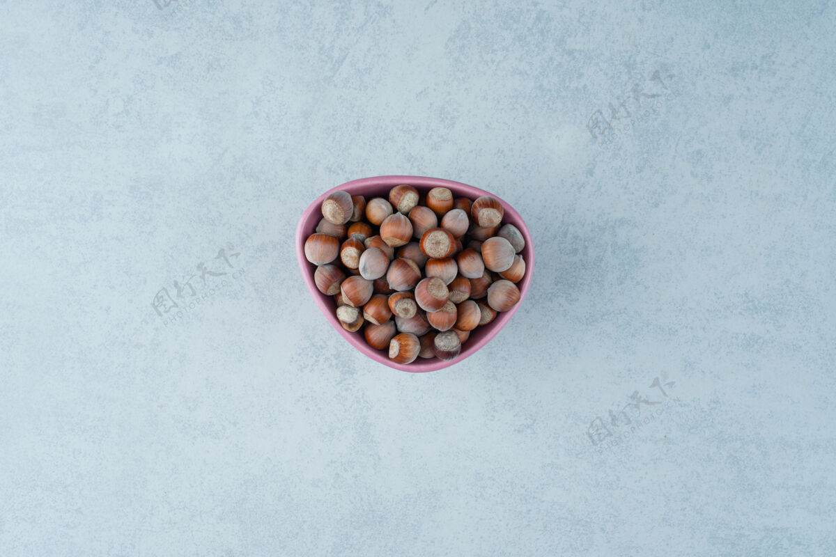 大理石在大理石背景上放满坚果的粉红色小盘高质量照片健康可口可食用
