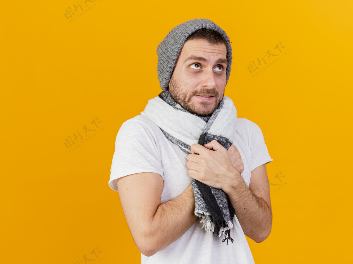 年轻寒冷的年轻人戴着冬天的帽子和围巾隔离在黄色的病号冻结寒冷黄色