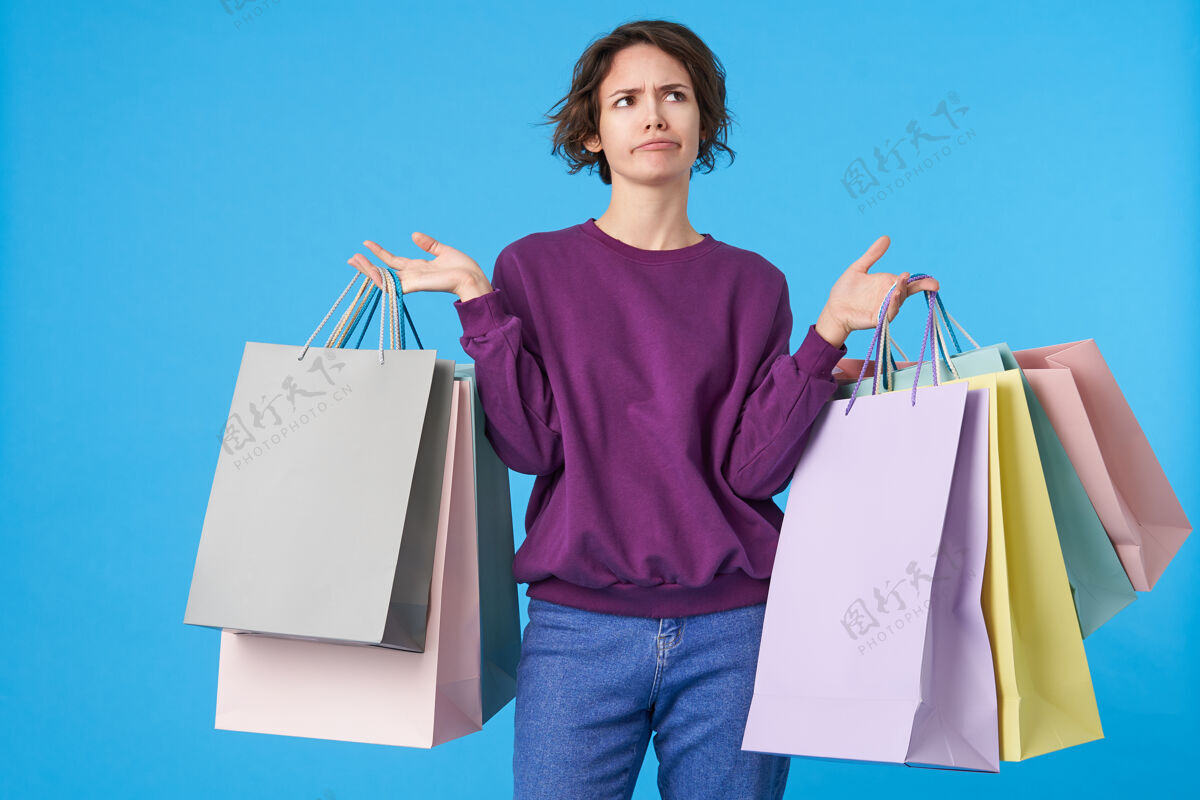 购物狂年轻迷人的黑发女人 短发 带着很多购物袋服务器站紫色