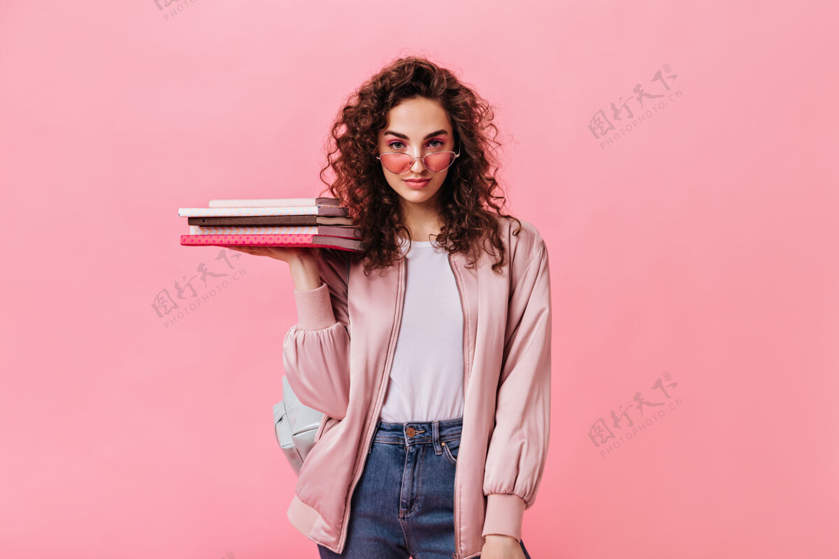 牛仔裤自信的女人 穿着时尚的日常服装 拿着粉色背景的书衣服生活方式休闲
