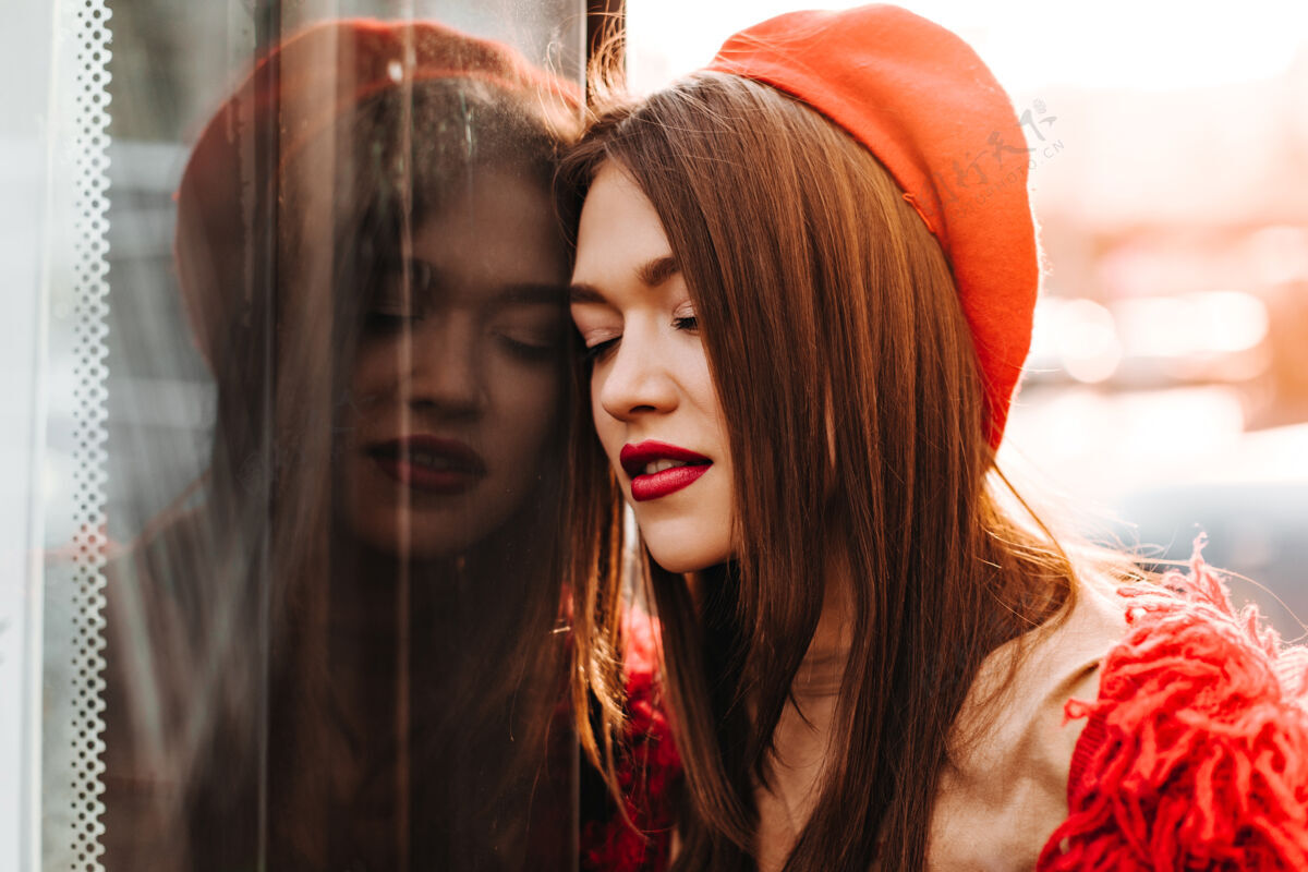 成功红唇女士戴着鲜艳的贝雷帽 穿着毛衣 靠在窗户上 在外面摆姿势欧式模特衣服