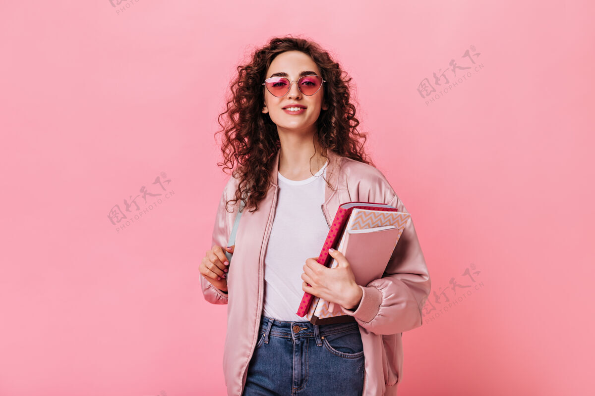 欢呼可爱的女士穿着粉红色的衣服 戴着墨镜拿着书针织愿望年轻
