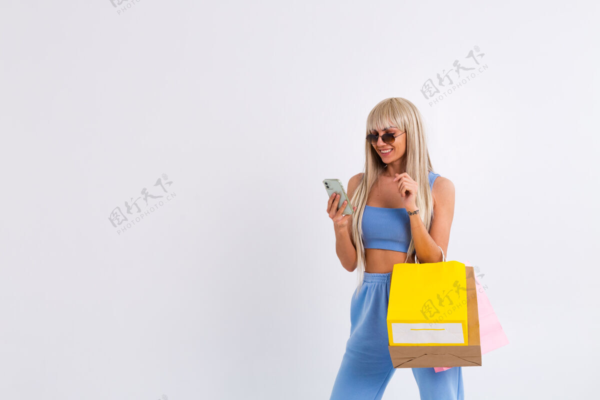 手机美丽的年轻女子直发带着漂亮的金发购物袋购物者购买折扣