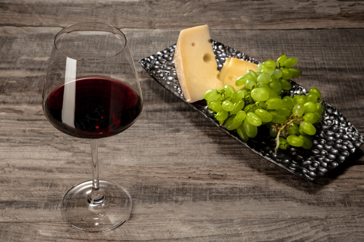 切片木桌上放着一瓶红酒和一杯水果开胃酒饮料乡村