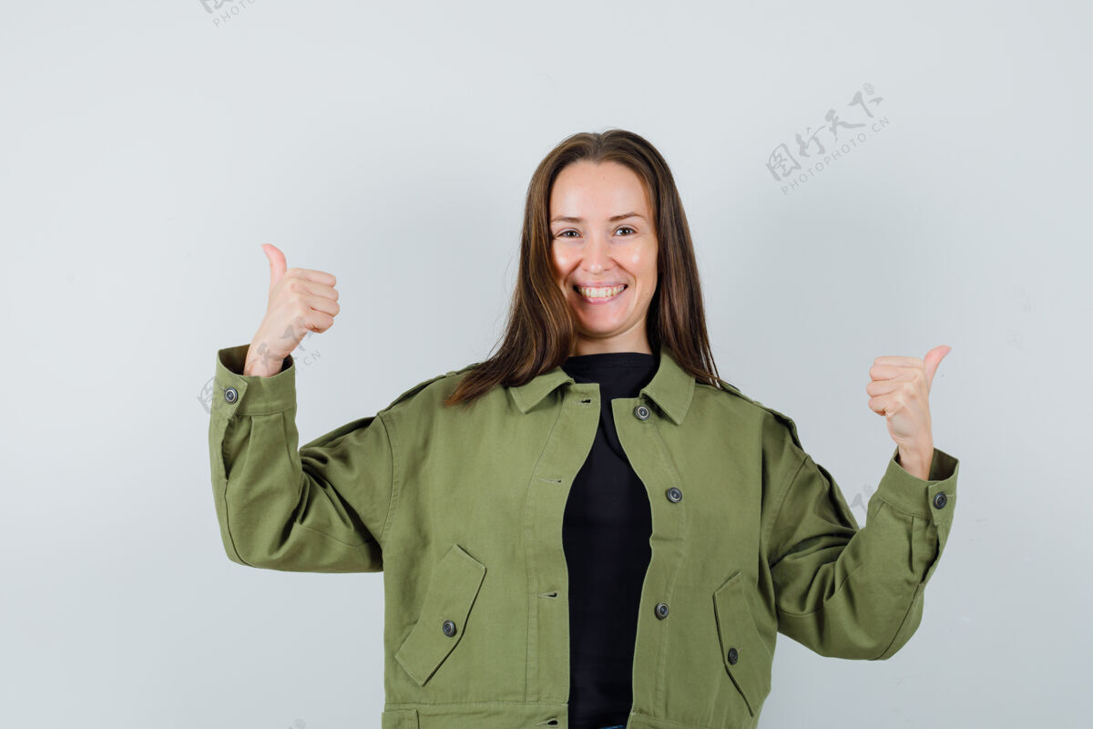 休闲穿着绿色夹克的年轻女子竖起大拇指 看上去很积极正面视图女人夹克微笑