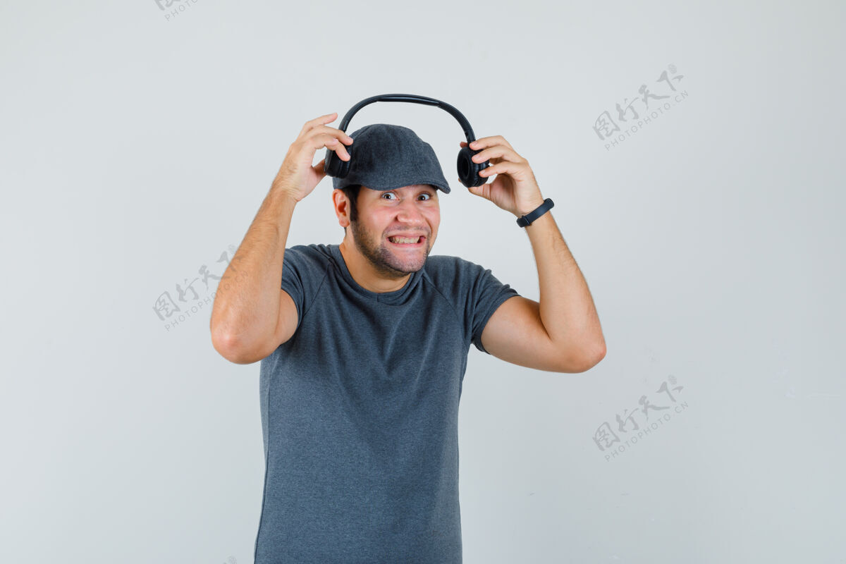 小年轻男子戴着耳机 穿着t恤 戴着帽子 看上去很快乐前视图年轻幼儿男人