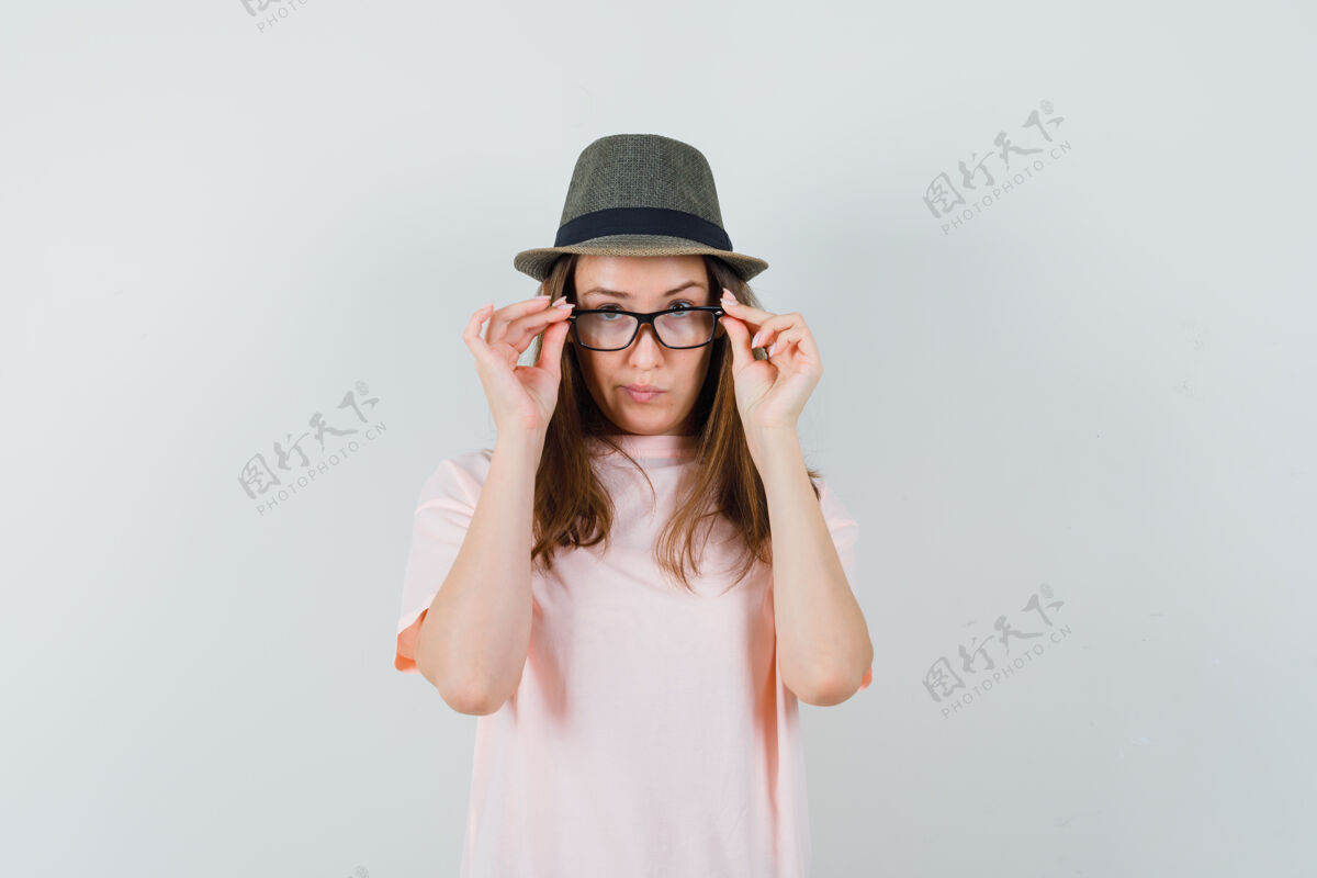 小穿着粉色t恤 戴着帽子的年轻女孩透过眼镜 神情犹豫不决微笑童年积极