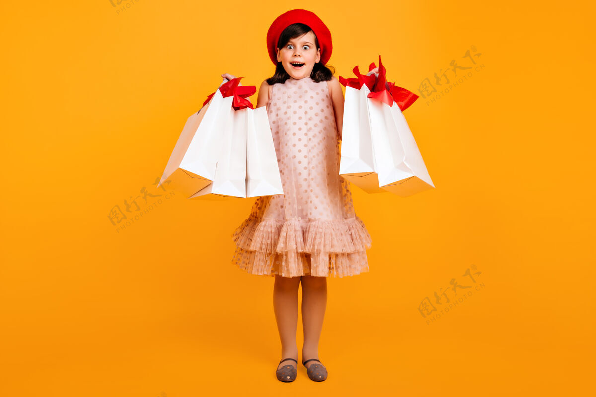 女性一个穿着法国贝雷帽的小女孩在购物后摆出一副惊讶的姿势带着纸袋的孩子惊呆了时尚休闲享受