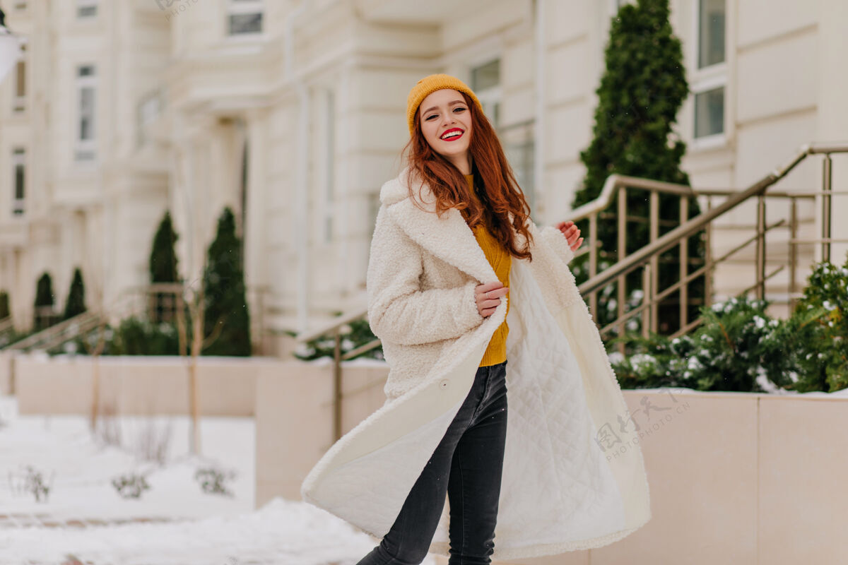 城市快乐的白人女子在寒冷的早晨跳舞无忧无虑的姜姑娘享受冬天的户外照片时尚积极乐趣