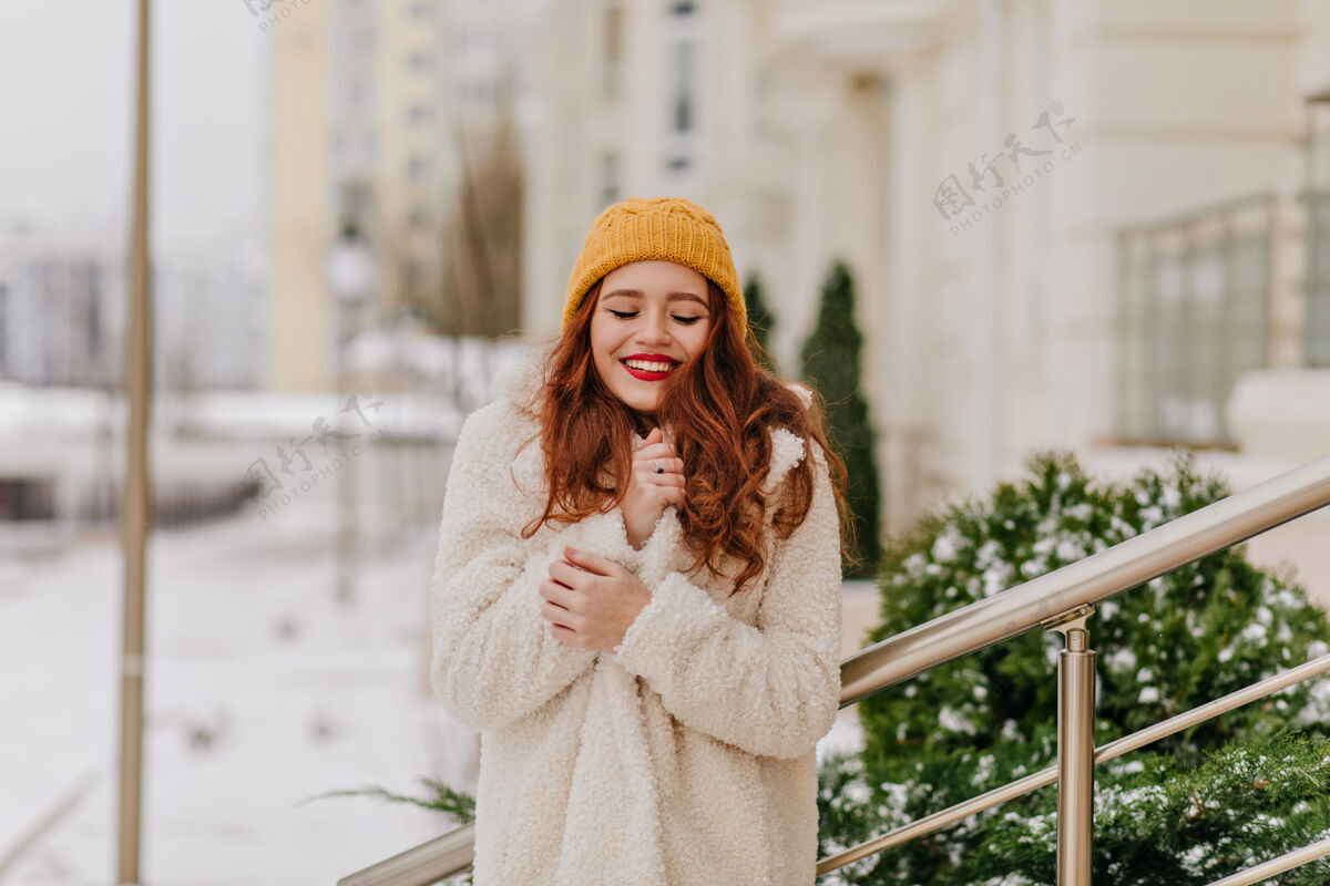散步优雅的姜黄色年轻女子在冬天摆姿势穿着时髦外套的白人女孩微笑着站在街上街头风格模特黑发