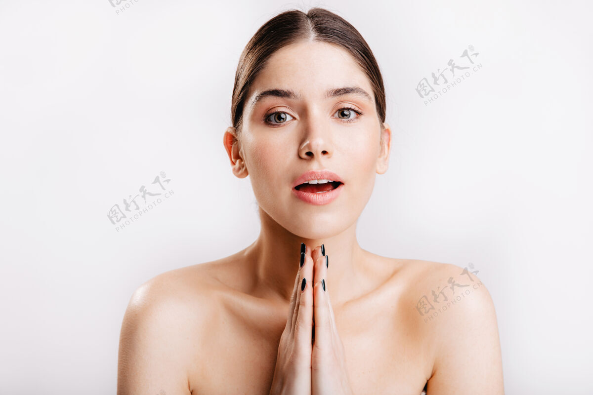 成人一张年轻女孩的特写照 她脸上没有化妆 双手合十 在白色的墙上做着祈祷的姿势漂亮脸部绿眼睛