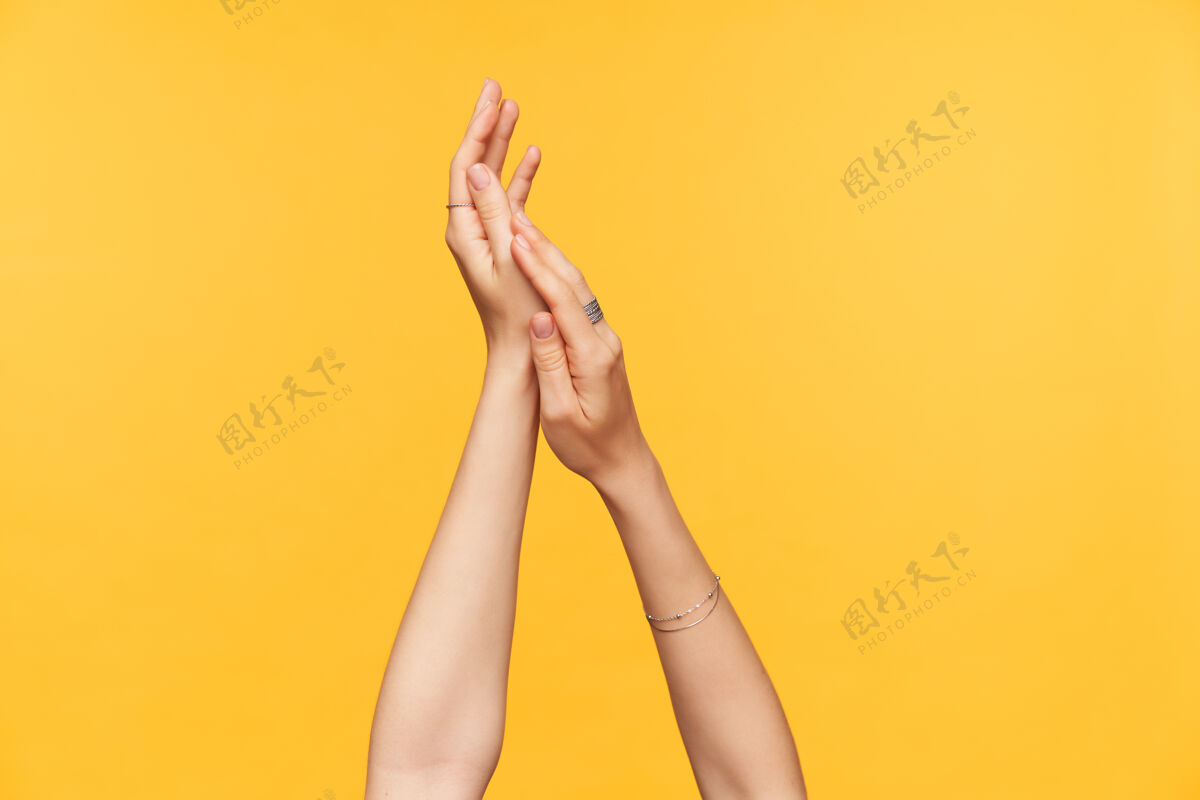 女性剪下的照片 年轻女性的手 皮肤白皙 修剪整齐 在涂奶油的时候被举起来 隔离在黄色背景上手和身体护理的概念沟通手臂护理