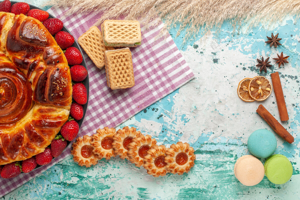 饼干俯瞰美味的派与红色草莓和华夫饼在蓝色的表面糖果糖果盘子