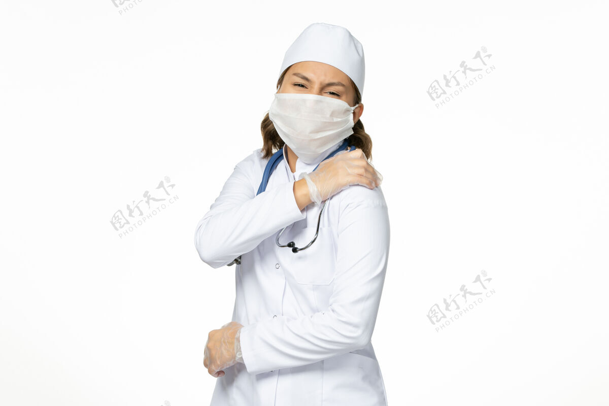 女性正面图：年轻的女医生 戴着无菌口罩和手套 因为浅白色的桌子上有冠状病毒病毒手套面罩