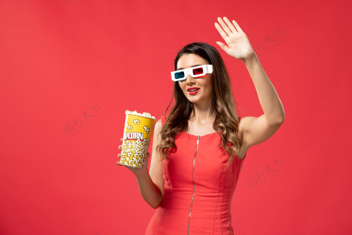 电影正面图年轻女性手持爆米花包戴着d墨镜在红色表面电影举行头发