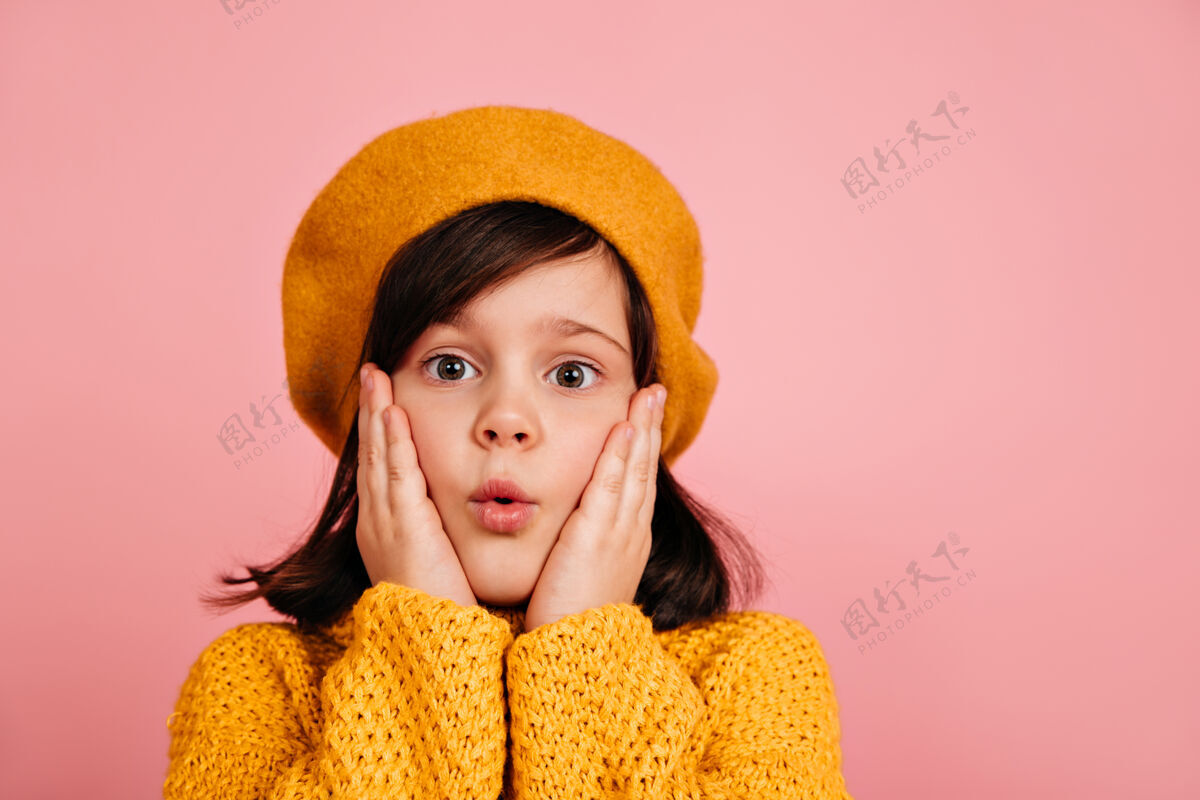 女孩惊艳女孩做鬼脸的特写镜头穿黄色贝雷帽的欧洲小孩时尚帽子毛衣