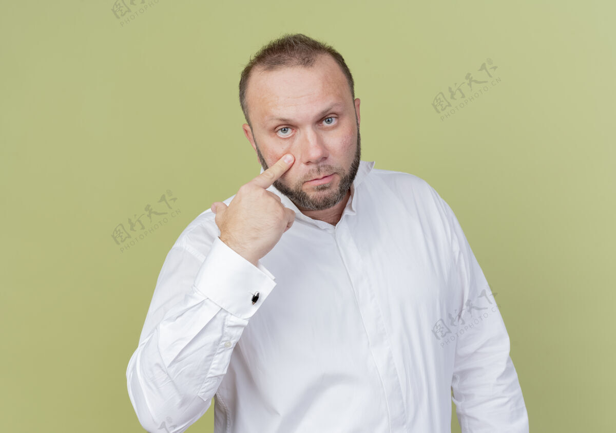 目录一个留着胡子的男人穿着白衬衫 用食指指着他的眼睛 看着你们站在轻墙上做手势男人穿手势