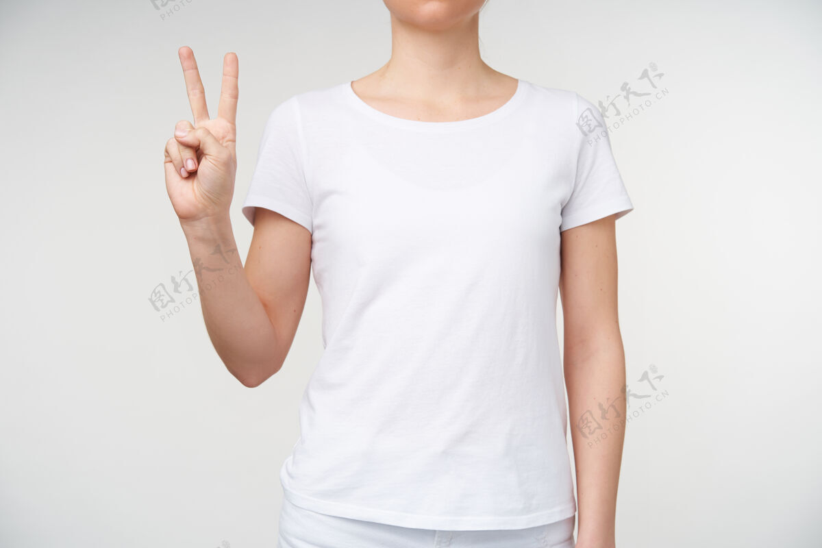 身体摄影棚的照片 年轻的女士显示两个手指 同时形成和平的姿态 用手语表示字母v 站在白色的背景白色提高女人
