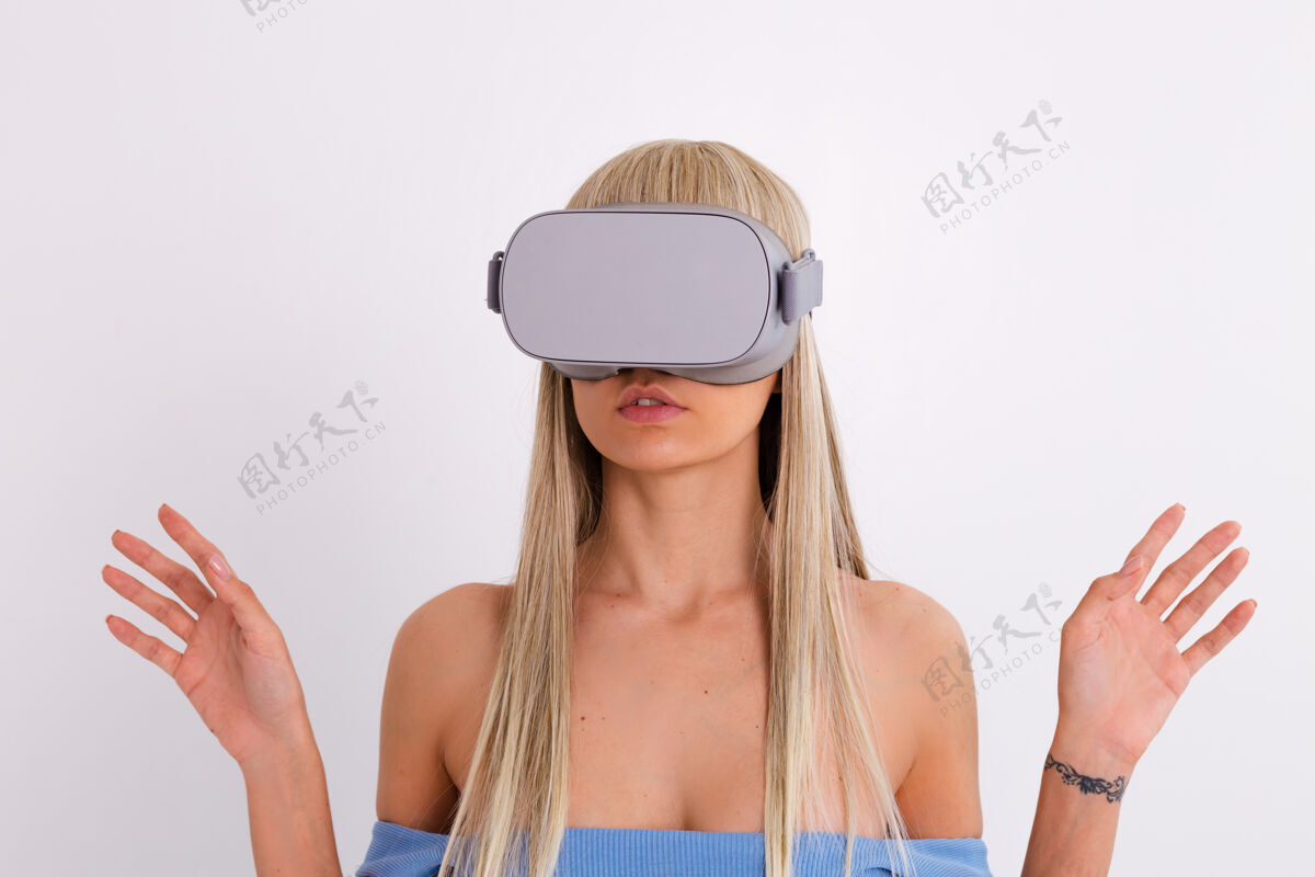 休闲摄影棚照片中一个年轻迷人的女子穿着温暖的蓝色时尚西装 戴着虚拟现实眼镜在白色的设备小玩意创新