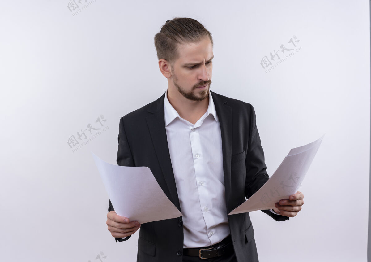穿着穿着西装的帅哥拿着白纸看着白纸 严肃的脸站在白色的背景上商业男人空白