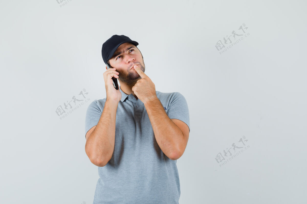 维护身着灰色制服的年轻技术员站在思考的姿势 一边打电话 一边沉思着谈话中心生产