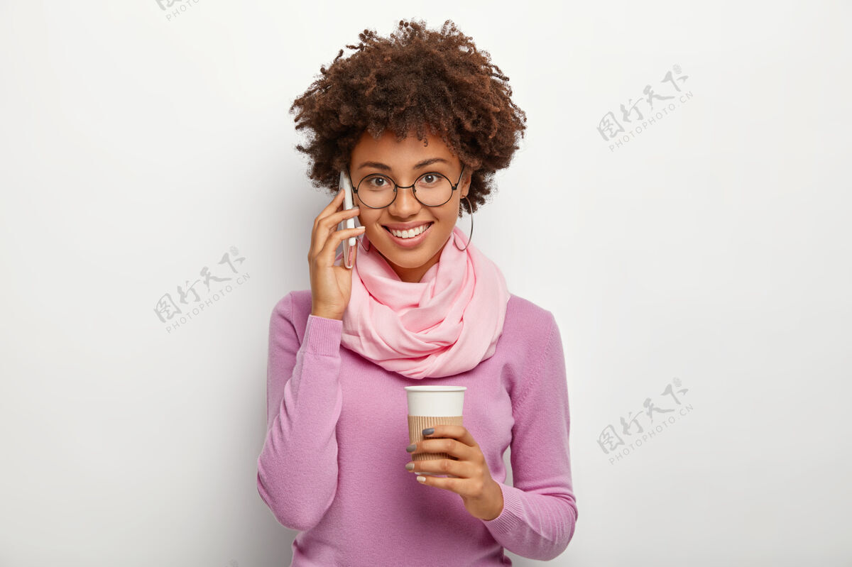 饮酒黑发清爽的美女头像 享受愉快的电话交谈 拿着外卖咖啡杯 戴着圆眼镜 紫色套头衫 健谈 运用现代科技非洲紫色个人