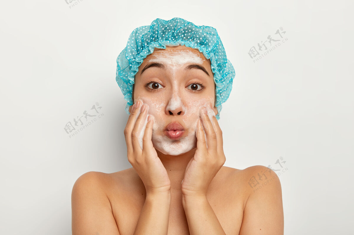 赤膊双唇合拢的可爱女性特写肖像 在脸上涂上肥皂 洗干净皮肤 裸体站立 呵护脸部卫生淋浴健康