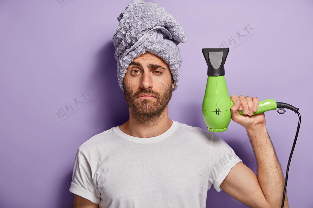 发型头发护理和美容概念瞌睡的男人拿着吹风机 淋浴后要做发型 头上戴着软毛巾猪鬃理发师独自