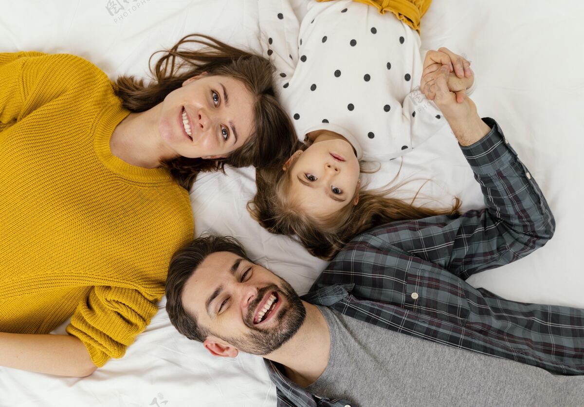 家庭中枪父母和孩子平躺在床上父母女人乐趣