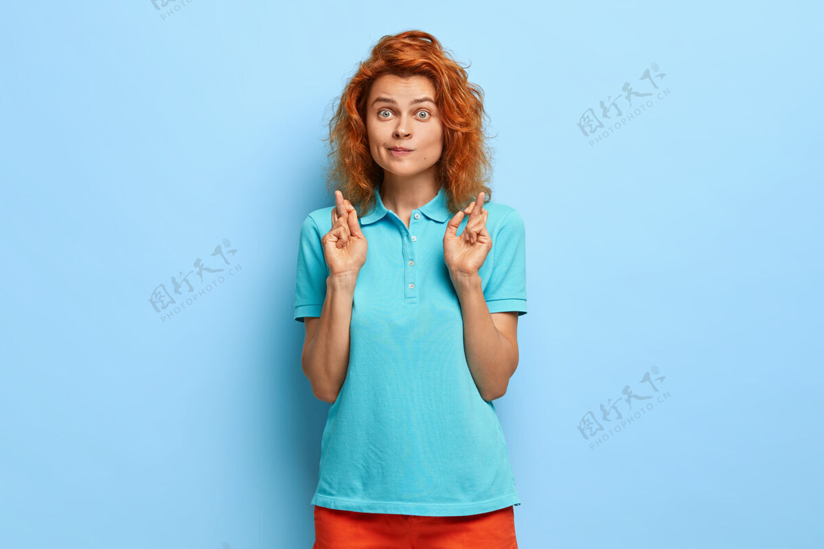女人大希望更好红头发惊讶的年轻女子交叉手指 做祈祷的手势 穿着休闲夏装思想女性女朋友