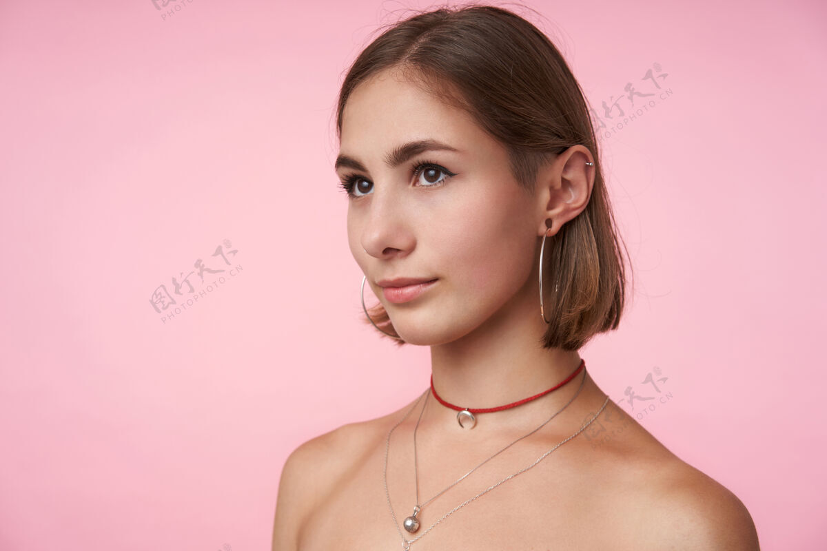 姿势年轻漂亮的棕色眼睛女人的肖像 留着鲍勃式的发型 嘴唇交叉着 一边轻轻地看着一边 手放在粉红色的墙上深色头发发型发型