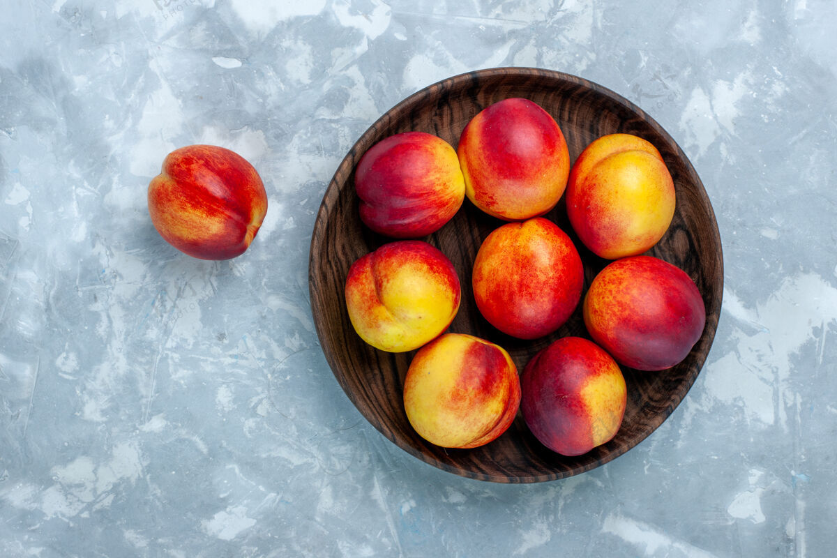 盘子顶视新鲜桃子醇厚可口的水果内棕色盘子浅白色表面水果内部健康