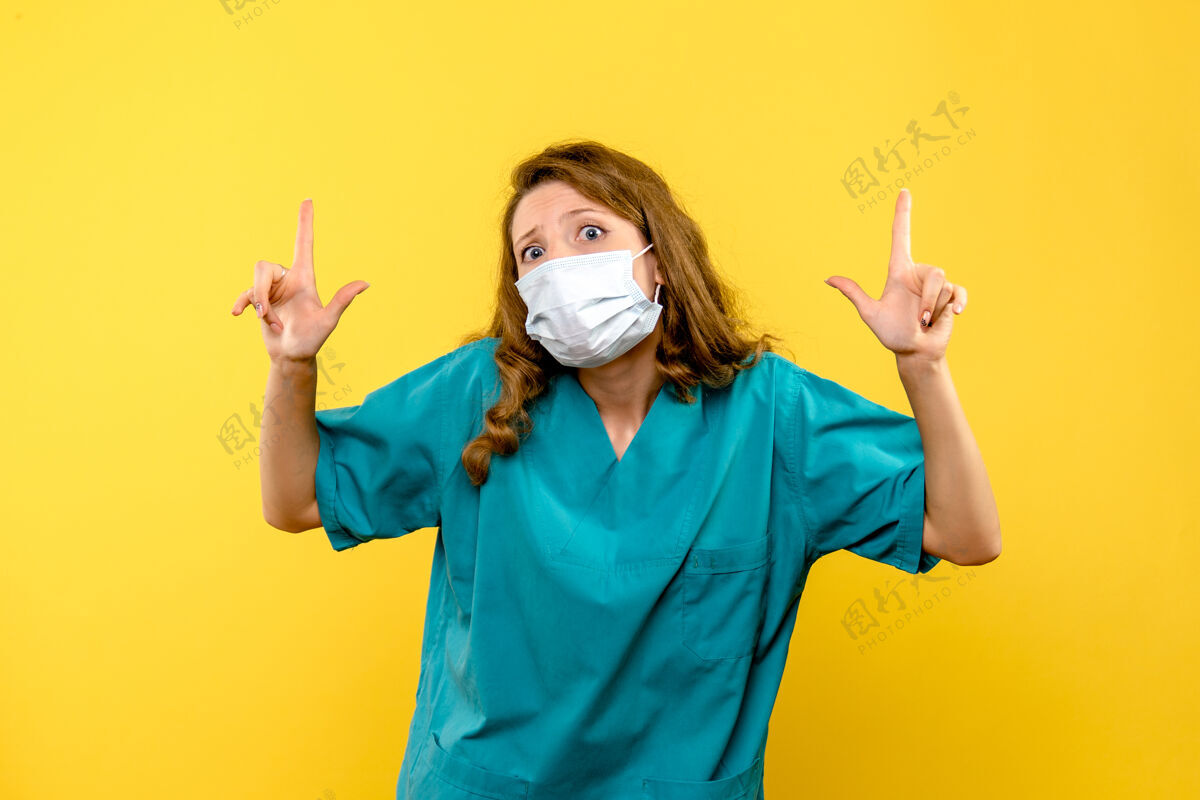 视图黄色空间里戴着面具的年轻女医生的正面图面具脸护士